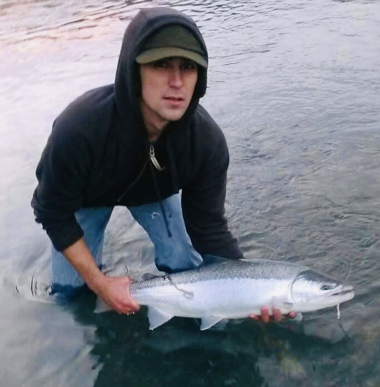 Maximo Macanas holding a salmon in a river.
